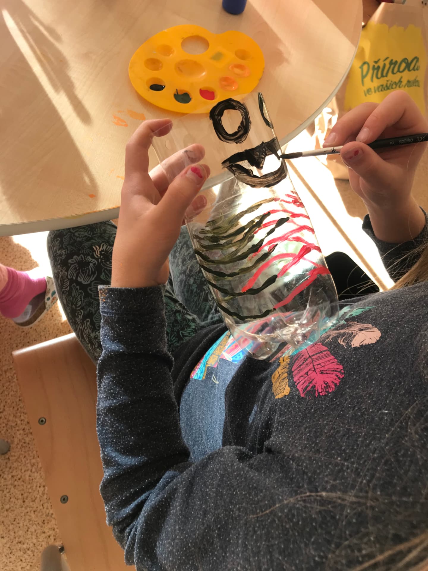 A hand with a brush working on transparent material